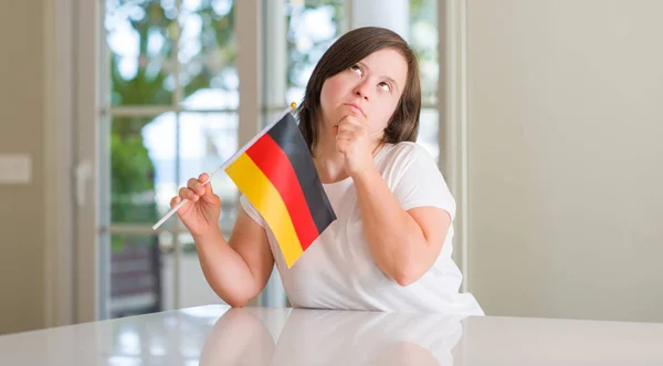 ドイツ深刻な顔を考えて質問 非常に混乱しているアイデアのホーム開催旗でダウン症女性 — ストック写真