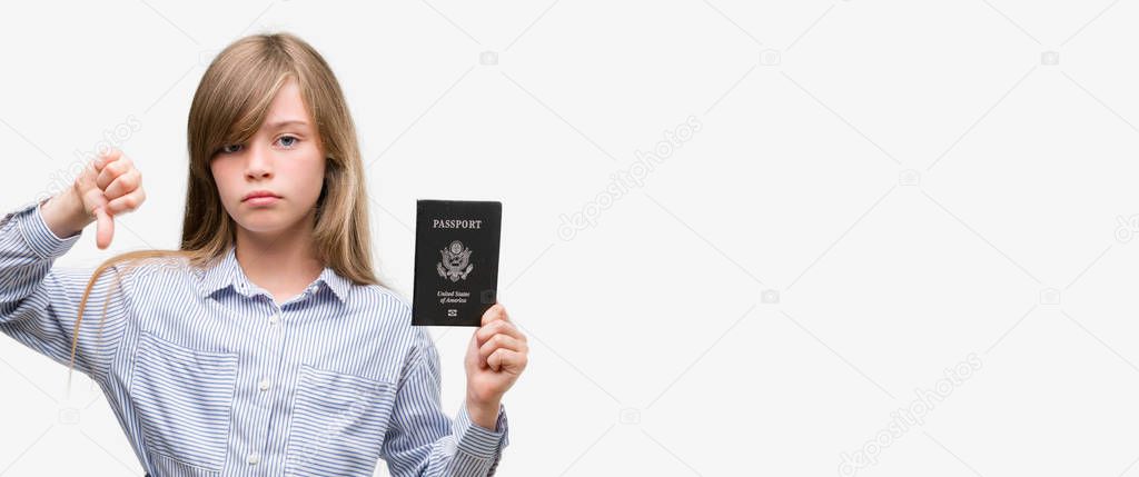 Young blonde toddler holding american passport with angry face, negative sign showing dislike with thumbs down, rejection concept