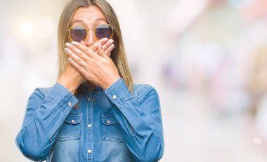 Genç güzel kadın üzerinde güneş gözlüğü takıyor arka plan ağız hata için elleriyle kapsayan şok izole. Gizli kavramı.