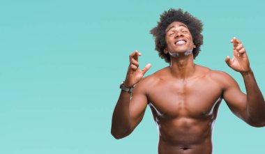 Çıplak vücut geçiş parmakları umut ve gözleri kapalı ile gülümseyen izole arka plan üzerinde gösterilen Afro Amerikalı gömleksiz adam. Şans ve batıl kavramı.