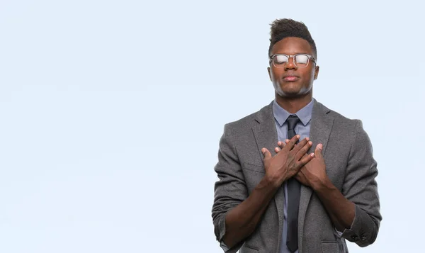 Young african american business man over isolated background smiling with hands on chest with closed eyes and grateful gesture on face. Health concept.