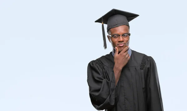 Young graduated african american man over isolated background looking confident at the camera with smile with crossed arms and hand raised on chin. Thinking positive.