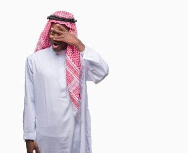 Mahcup ifadeyle parmaklarımın arasından seyir geleneksel keffiyeh yüz ve gözler el ile kapsayan şok bakmak izole arka plan üzerinde giyen genç Arapça Afrika adam.