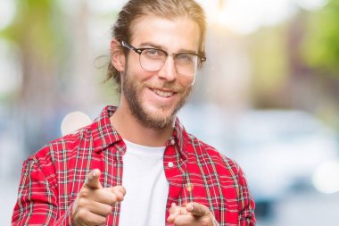 Gözlük kamera ile mutlu ve komik yüz için parmakları işaret izole arka plan üzerinde uzun saçlı Genç yakışıklı adam. İyi enerji ve vibes.