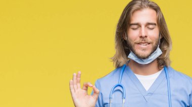 İzole arka plan üzerinde uzun saçlı Genç yakışıklı Doktor adam rahatla ve gülümseyen gözlerle kapalı parmak jestle meditasyon yapıyor. Yoga kavramı.