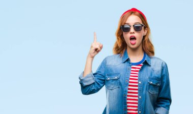 Genç güzel kadın yüzünden izole arka plan başarılı fikirle parmak işaret güneş gözlüğü takıyor. Çıktıktan ve mutlu. Bir numara.