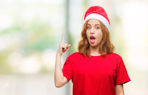 年轻美丽的女人在孤立的背景下戴着圣诞帽指着成功的想法 退出和快乐 第一个 — 图库照片