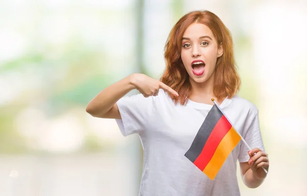 年轻美丽的妇女拿着旗子德国在隔绝的背景非常愉快指向用手和手指 — 图库照片