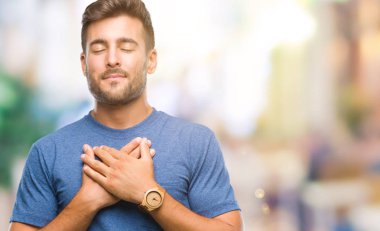 Yakışıklı delikanlı ile gülümseyen izole arka plan üzerinde kapalı gözler ve yüzünde minnettar jest ile göğüs üzerinde eller. Sağlık kavramı.