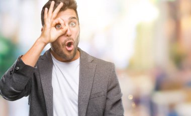 Genç yakışıklı iş adamı ok jest yapıyor izole arka plan üzerinde sürpriz yüz, göz parmaklarının arasından seyir ile şok. İmansız ifade.