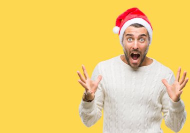 Üzerinde santa claus şapka giyen genç yakışıklı adam deli kutluyor arka plan izole ve başarı için kaldırdı kollarını açarak hayrete ve heyecanlı çığlık gözleri açık. Kazanan kavramı