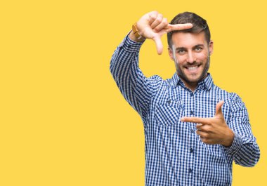 Yakışıklı delikanlı elle yapma çerçeve ve parmakları ile mutlu yüz gülümseyen izole arka plan üzerinde. Yaratıcılık ve Fotoğrafçılık kavramı.