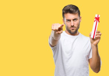 Kamera ve size parmak ile işaret izole arka plan üzerinde Sevgililer günü hediyesi veren aşık genç yakışıklı adam, el işareti, pozitif ve kendinden emin bir jest ön