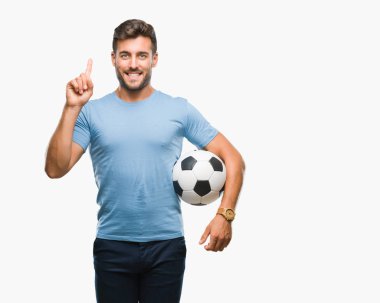 Yakışıklı delikanlı futbol futbol topu izole arka plan üzerinde bir fikir ya da soru işaret parmağı gülen yüz, bir numara ile sürpriz holding