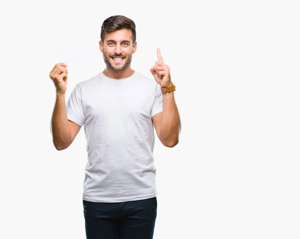 Jovem Homem Bonito Segurando Cartão Branco Sobre Fundo Isolado Surpreso — Fotografia de Stock