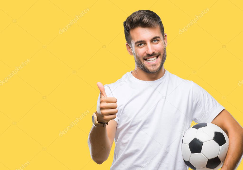 Young handsome man holding soccer football ball over isolated background happy with big smile doing ok sign, thumb up with fingers, excellent sign