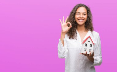 Genç İspanyol gerçek durum Aracısı kadın holding küçük ev parmak, mükemmel sembolü ile ok işareti yapıyor