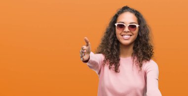 Güzel genç İspanyol kadın giyiyor güneş gözlüğü kamera ile gülümseyen seyir silah sarılmak için açın. Neşeli ifade kucaklayan mutluluk.