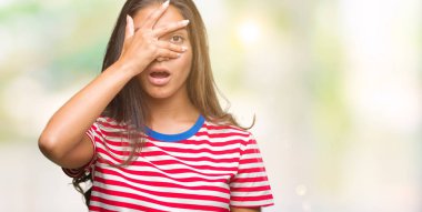 Yüz ve gözler el ile kapsayan şok bakmak izole arka plan üzerinde genç güzel Arap kadın mahcup ifadeyle parmaklarımın arasından arıyorsunuz.