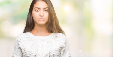 Yüzünde ciddi bir ifade ile izole arka plan üzerinde kış kazak giyen genç güzel Arap kadın. Basit ve doğal kameraya bakıyor.