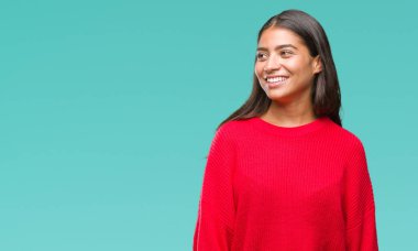 Üzerinde kış kazak giyen genç güzel Arap kadın arka plan uzak tarafına gülümseme ile yüzünde, doğal ifade arıyorum izole. Kendine güvenen gülüyor.