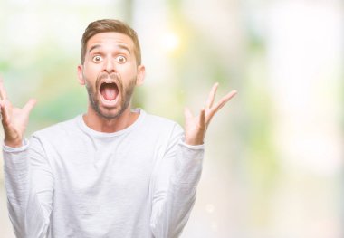 Yakışıklı delikanlı deli kutluyor ve silah ile başarı için heyecanlı çığlık kaldırdı ve açık gözleri hayret izole arka plan üzerinde. Kazanan kavramı