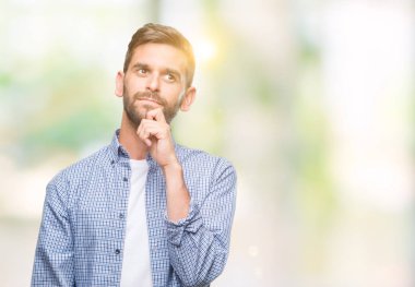 Çene düşünme hakkında soru, dalgın ifade üzerine el ile izole arka plan üzerinde beyaz t-shirt giyen genç yakışıklı adam. Düşünceli yüzüyle gülümsüyor. Şüphe kavramı.