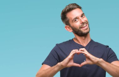 Yakışıklı delikanlı aşık kalp simgesi ve elleriyle şekil gösteren gülümseyen izole arka plan üzerinde. Romantik kavramı.