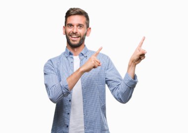 Gülümseyen ve iki elleri ve parmakları ile tarafına işaret kamera bakarak izole arka plan üzerinde beyaz t-shirt giyen genç yakışıklı adam.