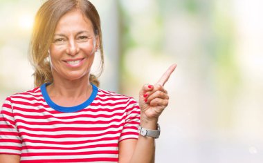 Kameraya bakarak yan el ve parmak ile işaret orta yaş İspanyol kadın kıdemli yüzünde kocaman bir gülümseme ile izole arka plan üzerinde.