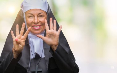Orta yaş üst düzey Hıristiyan Katolik Rahibe kadın gösterilen ve parmakları ile işaret izole arka plan üzerinde numara 9 kendinden emin ve mutlu gülümseyerek süre.