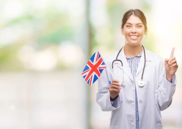 Joven Doctora Hispana Sosteniendo Bandera Del Reino Unido Sorprendida Con —  Fotos de Stock