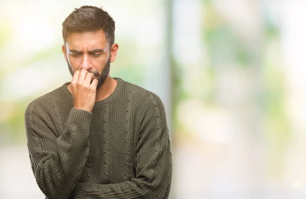 成年拉美裔男子穿着冬季毛衣在孤立的背景下 看着压力和紧张的嘴咬指甲的手 焦虑问题 — 图库照片
