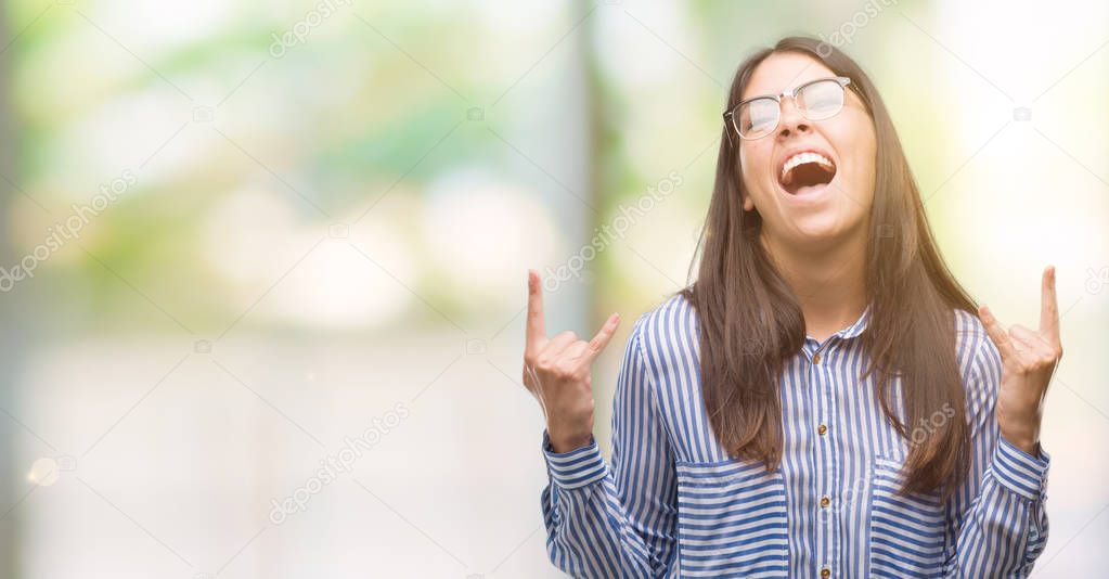Young beautiful hispanic business woman shouting with crazy expression doing rock symbol with hands up. Music star. Heavy concept.