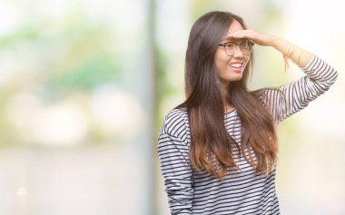 Üzerinde gözlük takan Genç Asyalı kadın arka plan çok mutlu ve gülümseyen uzakta el ile üzerine kafa seyir izole. Arama kavramı.