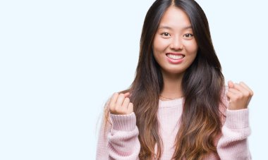 Genç Asyalı kadın kutluyor izole arka plan üzerinde şaşırttı ve başarı için kaldırdı kollarını açarak hayret ve gözleri açık. Kazanan kavramı.