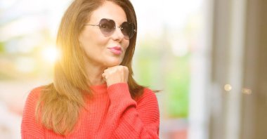 Orta yaş kadın düşünme ve şüphe ve merak ifade arıyorum kalp güneş gözlüğü takıyor