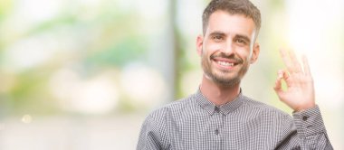 El ve parmak ile ok işareti yapıyor olumlu gülümseyen genç hipster adam. Başarılı ifade.