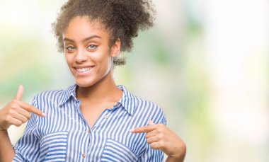 Yüzünde gülümseme ile kendinden emin görünüyorsun, kendini gururlu ve mutlu parmakları ile işaret izole arka plan üzerinde genç afro Amerikalı kadın.