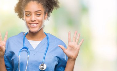 Genç afro Amerikalı doktor kadın gösterilen ve parmakları ile işaret izole arka plan yüzünden kendinden emin ve mutlu gülümseyerek süre yedi numara.