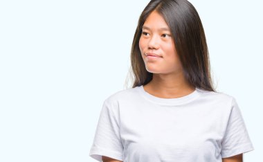 Genç Asyalı kadın görünümlü yan ve dik dik bakma uzağa düşünce gülümseyen izole arka plan üzerinde.