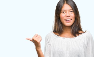 Genç Asyalı kadın arıyorum ve başparmak yanında yukarıyı mutlu yüz ile gülümseyen izole arka plan üzerinde.