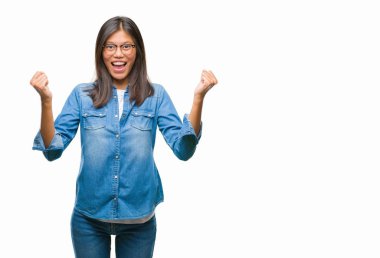 İzole arka plan üzerinde kutluyor gözlük takan Genç Asyalı kadın şaşırttı ve silah ile başarı için yükseltilmiş ve açık gözler hayrete düşürdü. Kazanan kavramı.
