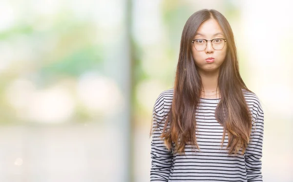 若いアジアの女性が変な顔で頬に息を切らし孤立の背景にメガネを着用します クレイジー式空気で膨らませ口 — ストック写真