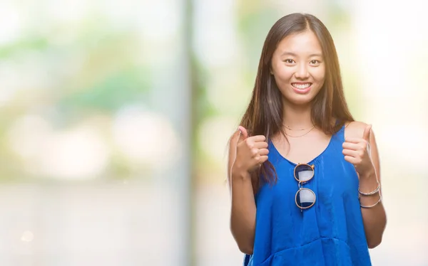 若いアジア女性の手で肯定的なジェスチャーを行う分離背景成功記号の上の親指を笑顔と幸せ 勝者ジェスチャー晴れやかな表情でカメラを見てください — ストック写真