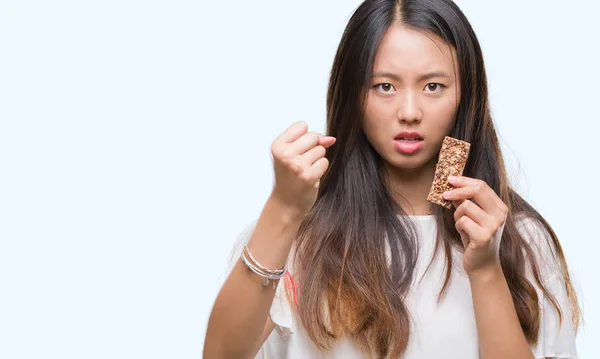 Young Asian Woman Eating Chocolate Energetic Bar Isolated Background Annoyed — Stock Photo, Image