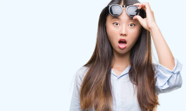 年轻的亚洲妇女戴着太阳镜在孤立的背景下害怕和震惊惊讶的表情 恐惧和兴奋的脸 — 图库照片