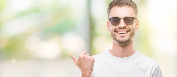 Young Tattooed Adult Man Wearing Sunglasses Pointing Showing Thumb Side — Stock Photo, Image