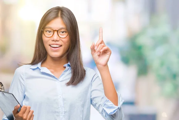 独立背景下的年轻亚洲商业女性持有剪贴板惊讶于一个想法或问题 手指与快乐的脸 — 图库照片