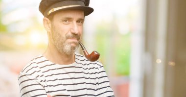 Kaptan gemici tütün pipo kendinden emin ve mutlu bir büyük doğal gülümseme gülmek ile çapraz kollu